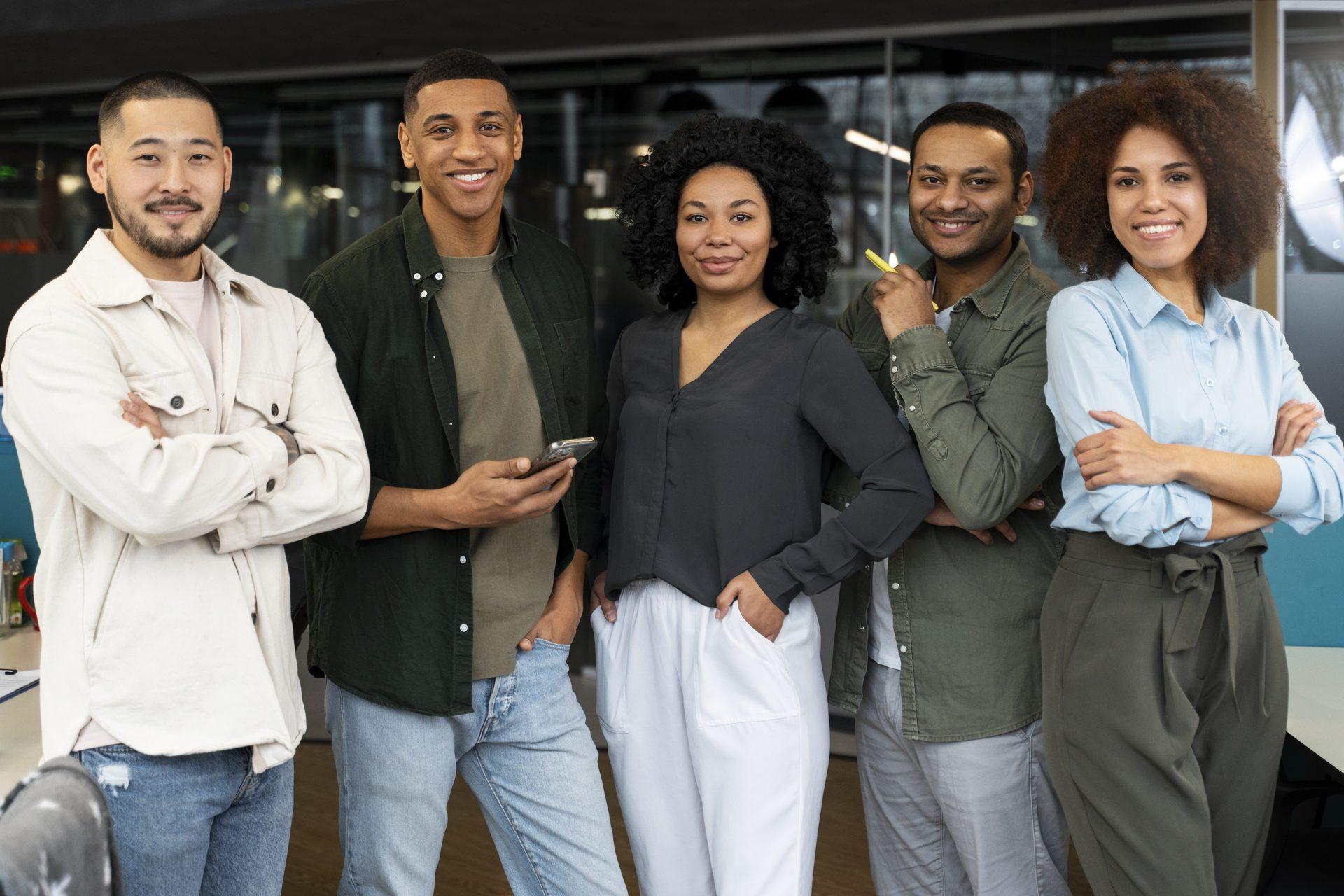 Un groupe de cinq personnes diverses, debout ensemble en tenue professionnelle décontractée